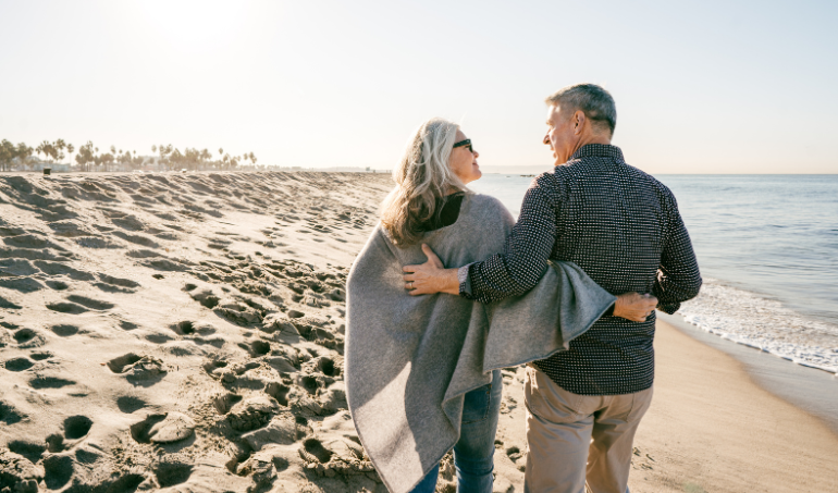 Older couple on the beach with their hands around each other