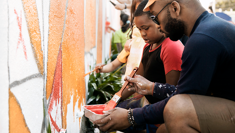 Man and young boy painting a mural