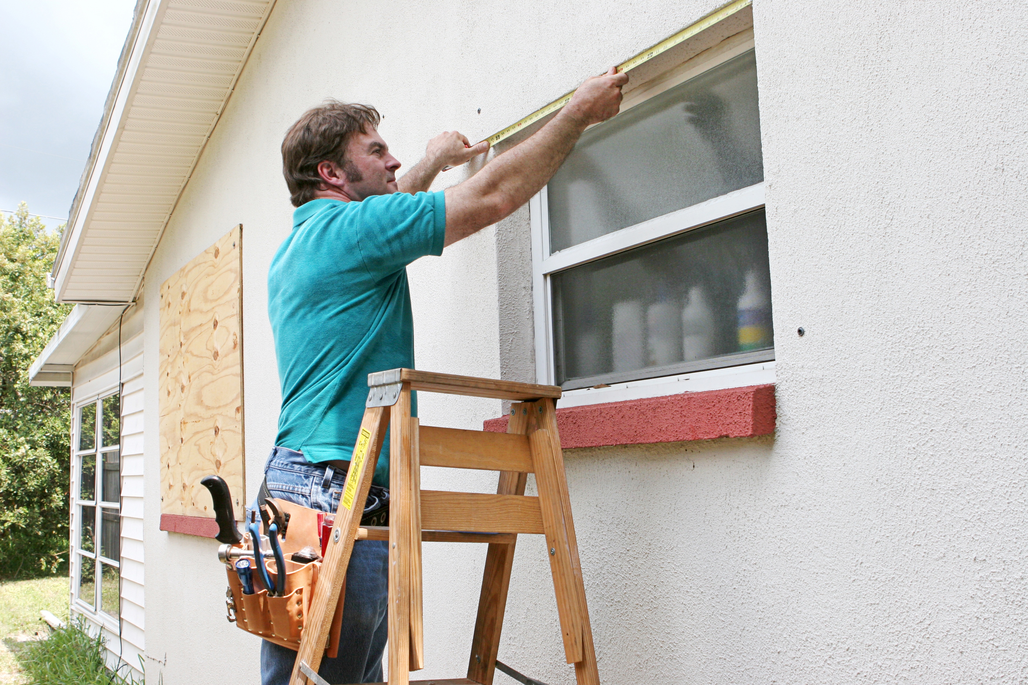 Man putting wood on window in preparation for hurricane
