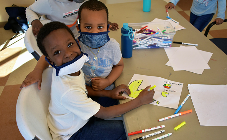 Two young boys smiling while coloring a picture
