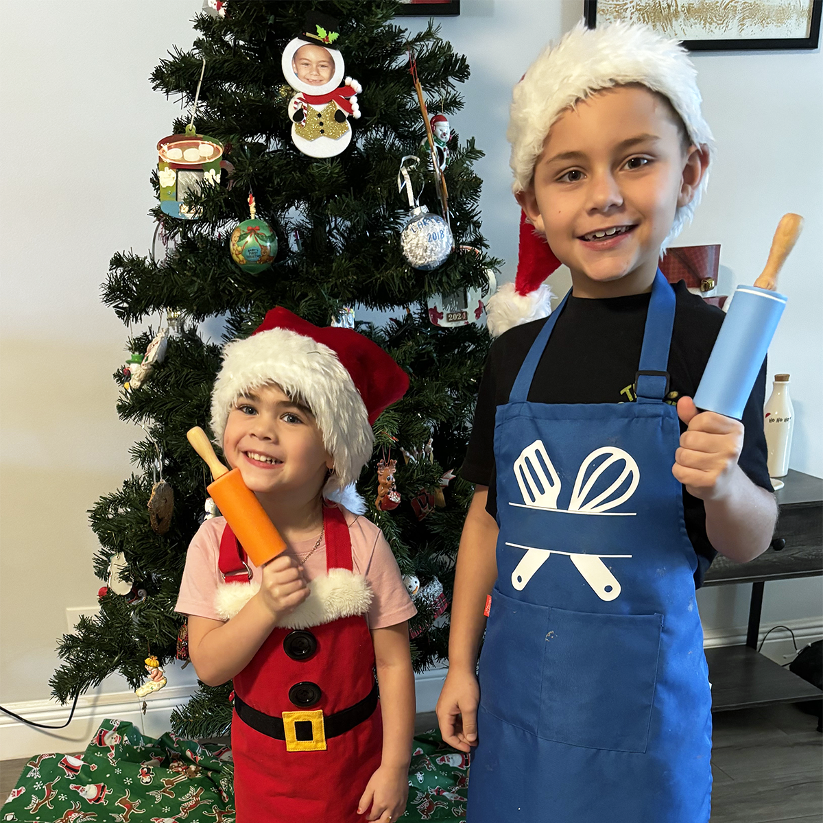 Carey’s grandchildren, ages 8 and 3, holding rolling pins and wearing aprons