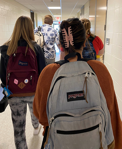 Students walking down a hallway with backpacks on
