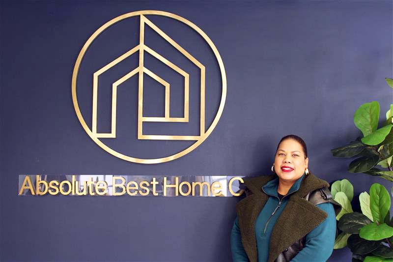Nadia Newman in front of the sign for her business