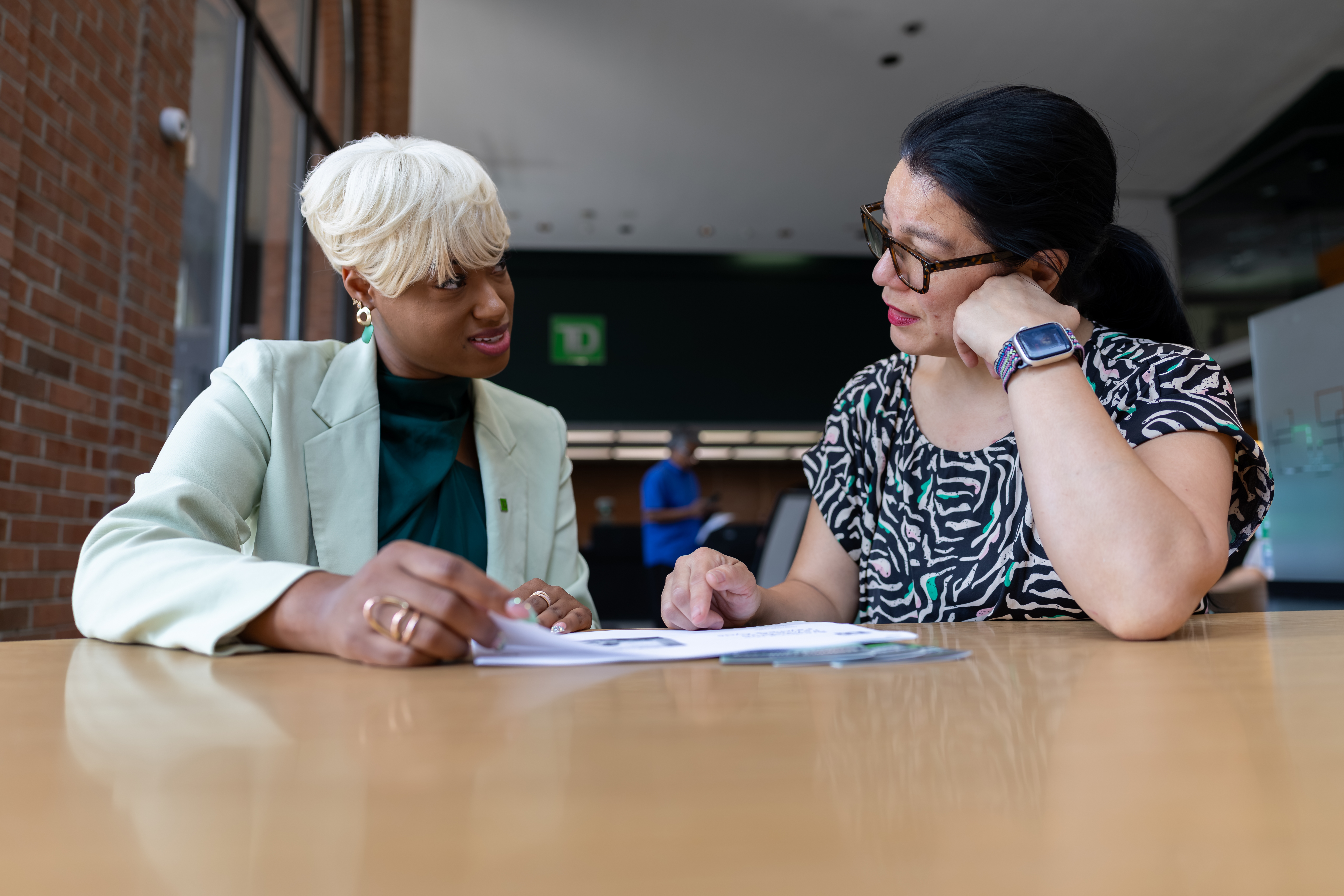 Two people talking at a table with documents
