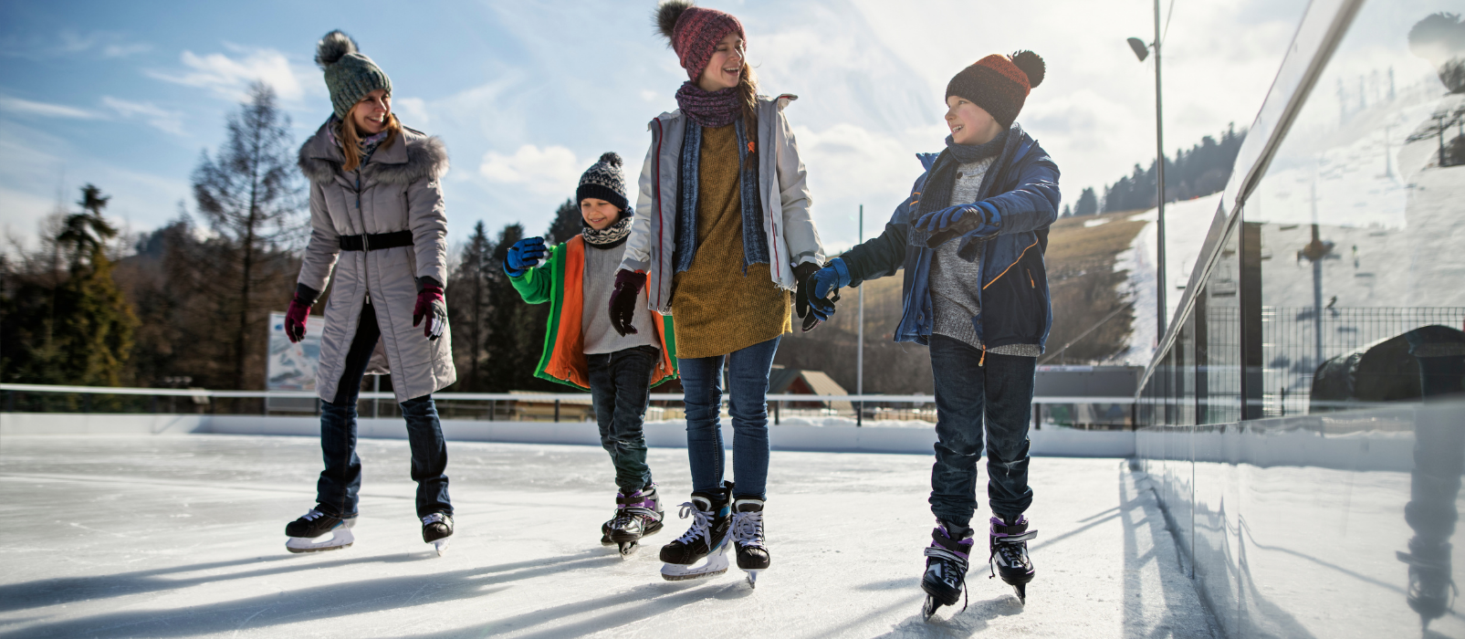 Woman ice skating with two young boys and a girl