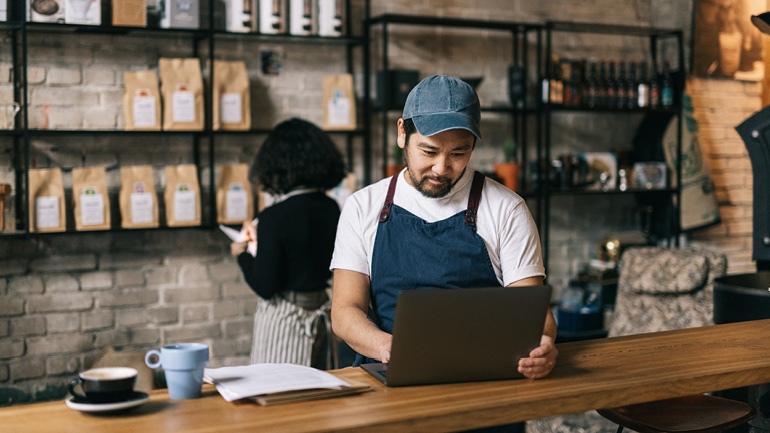 Small business owner checking his laptop instore