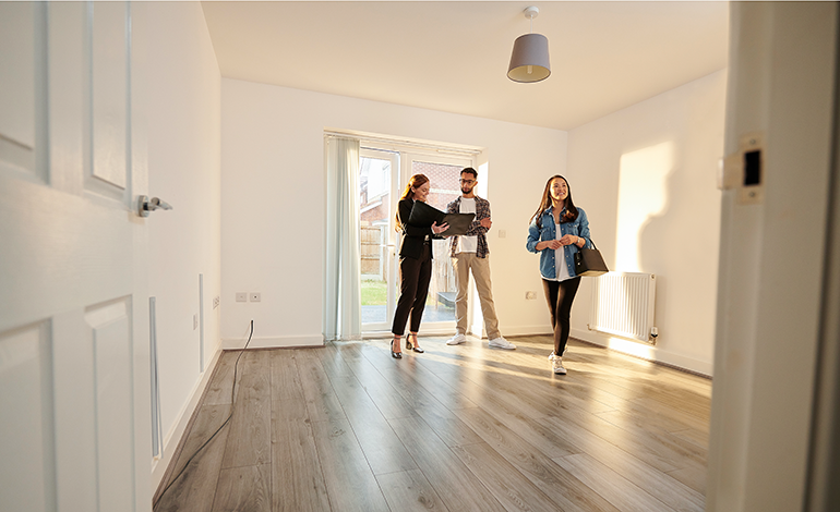 Couple looking inside a new house with a realtor.