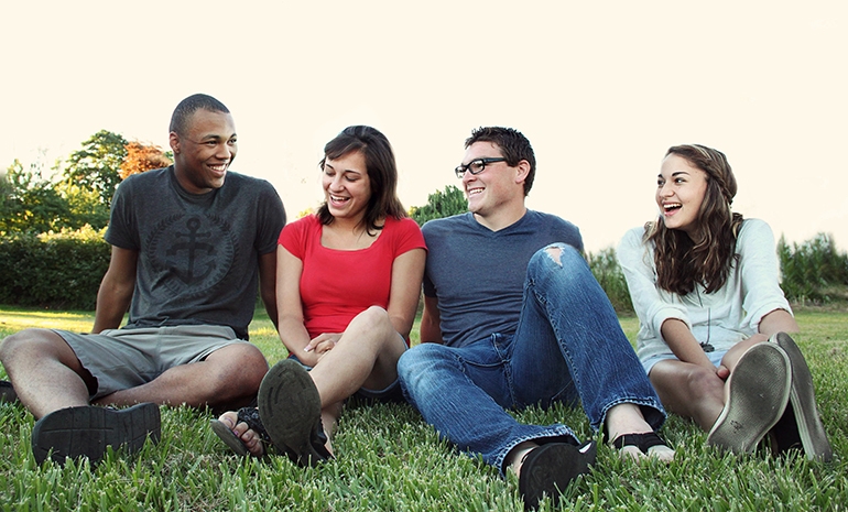 group of people sitting on grass and smiling