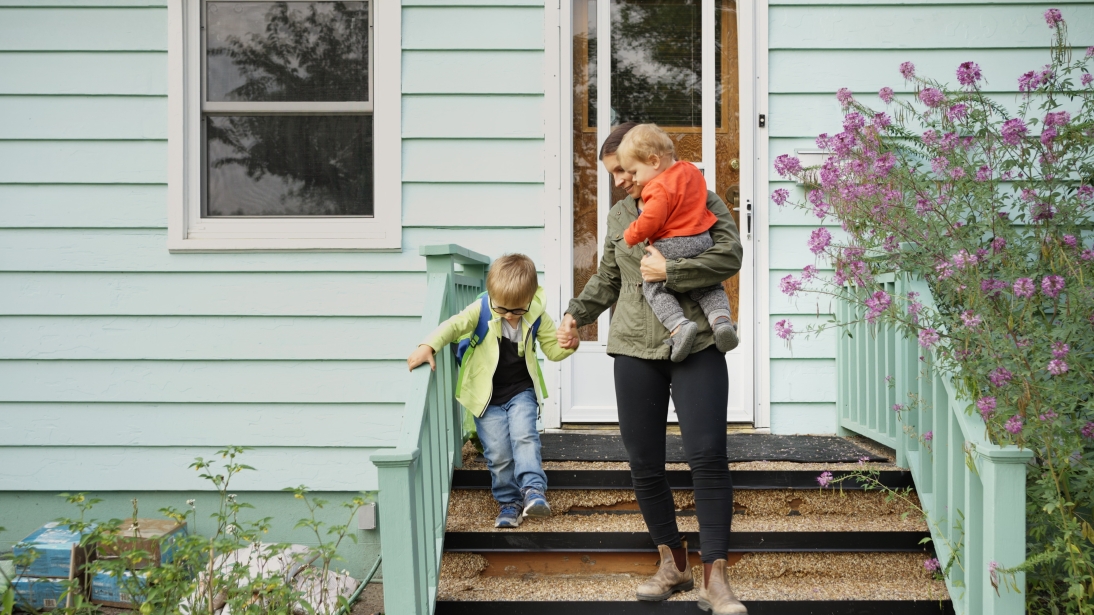 Woman and child leaving home in clothing fit for rainy weather.