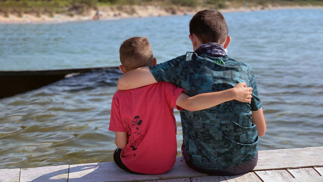 two boys sitting on a dock