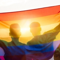 Two individuals holding up a pride flag.