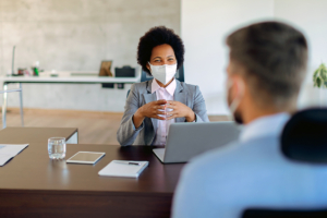 woman with facemask speaking to male coworker