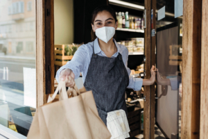 Woman wearing mask handing off shopping bags