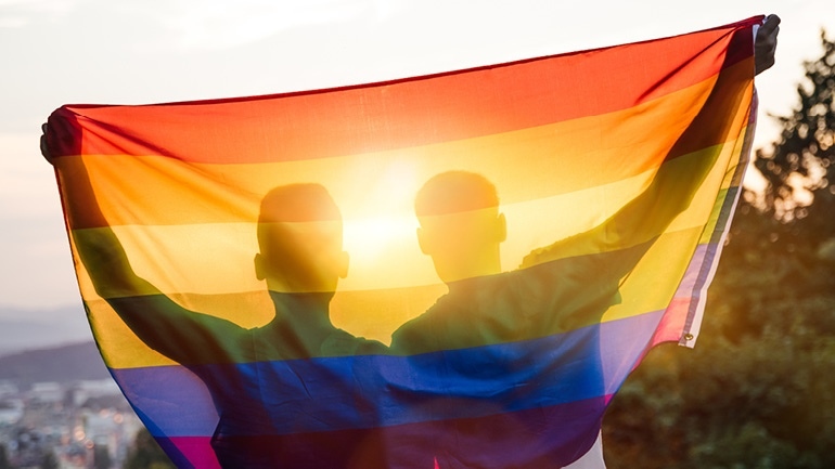 Two individuals holding up a pride flag.