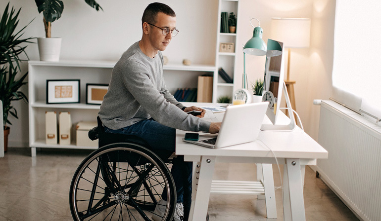 Young man in wheelchair works from home.