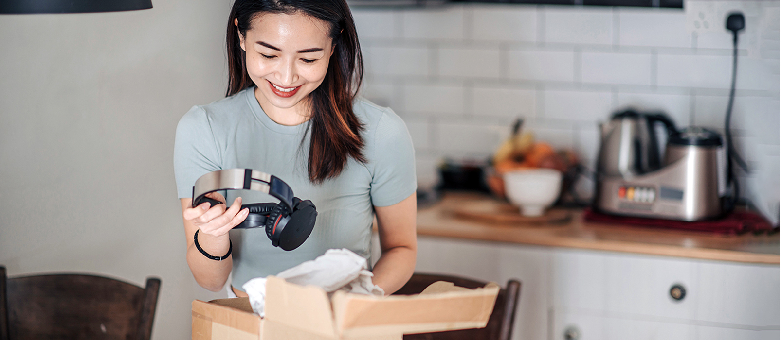 Smiling woman unpacking a box with headphones in it