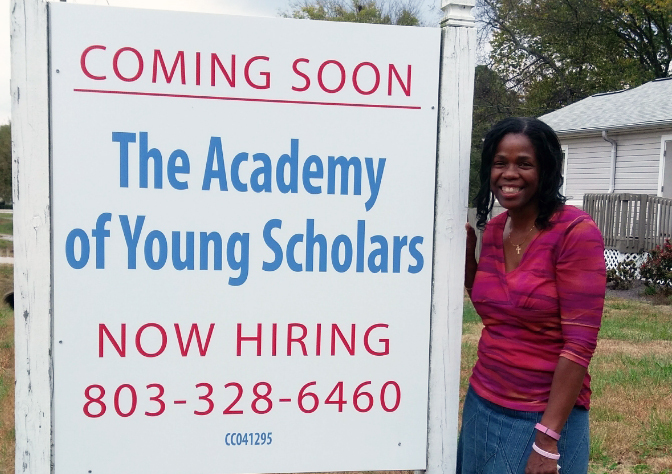 Helen Barnes in front of The Academy of Young Scholars sign