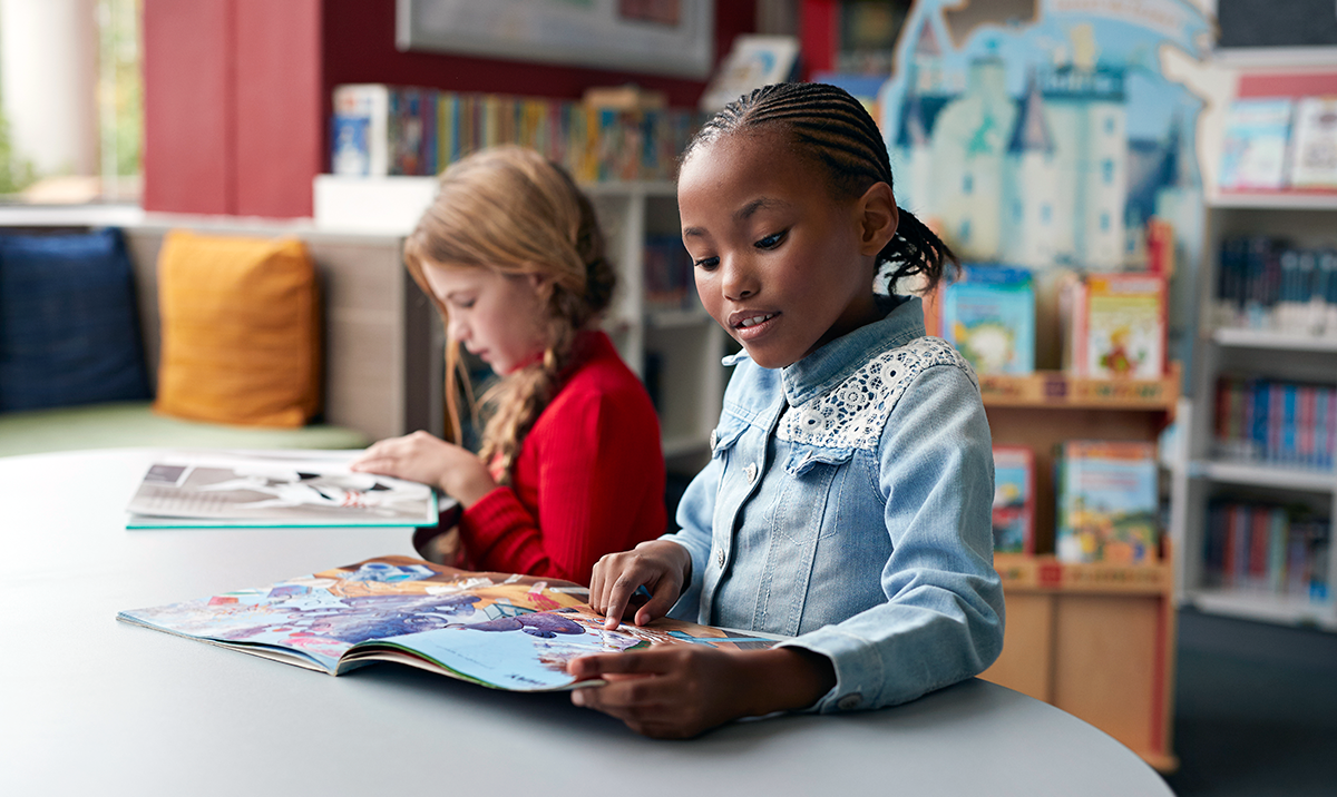 Two young girls reading in a classroom