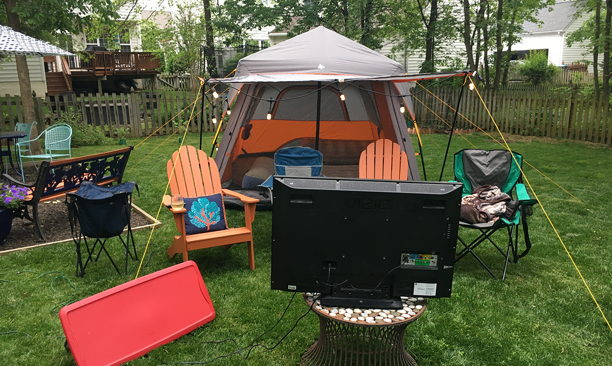 Backyard set up with a tent, chairs, and a TV