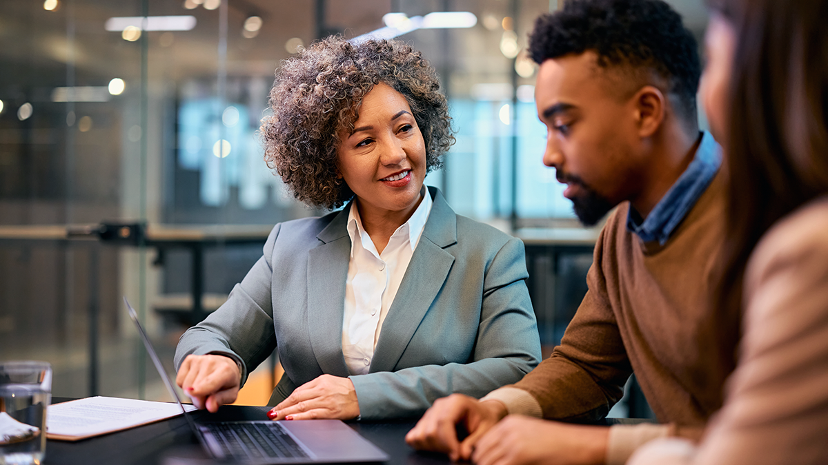 Woman financial advisor speaking to a man with a laptop open in front of them