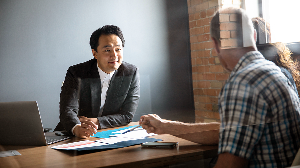 Male financial advisor talking to a couple with open documents in front of them