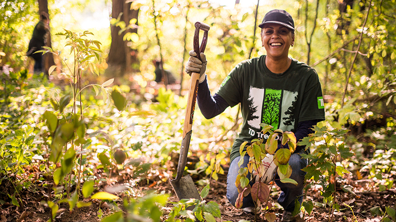Woman in a TD Tree Days t-shirt planting trees in a forest