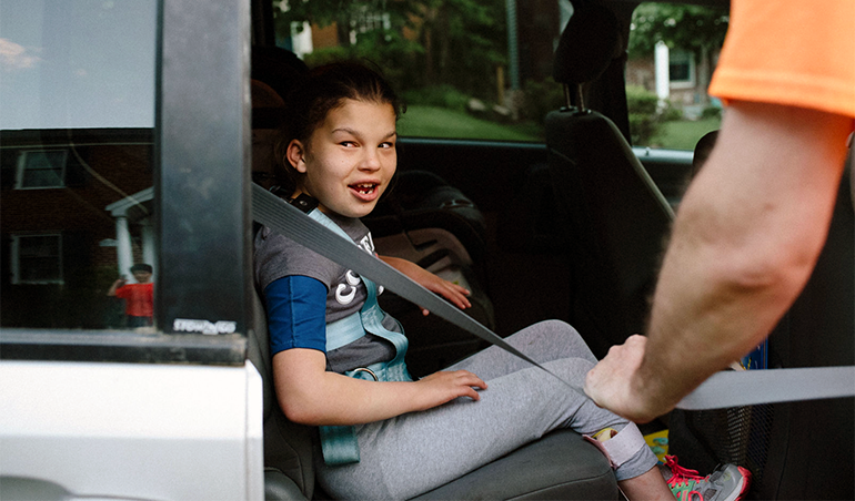 young girl being put in a car seat