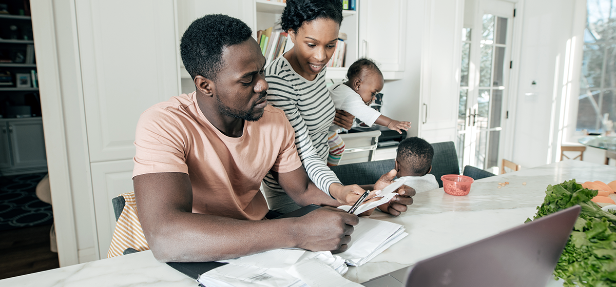 Man looking at documents with a woman behind her holding a young baby