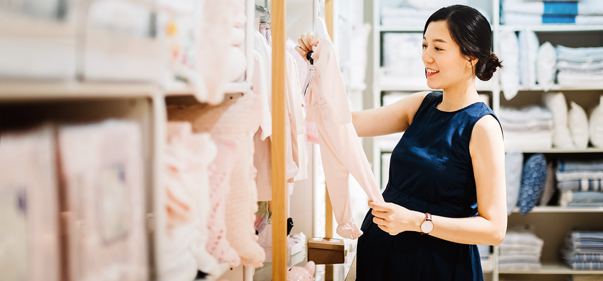 Pregnant woman looking at baby clothes
