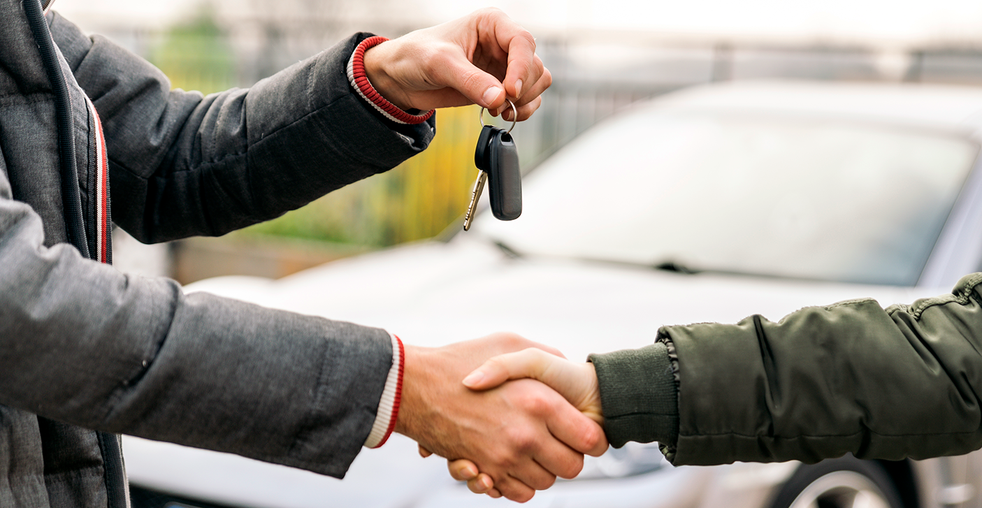 close up of two people shaking hands while handing over car keys