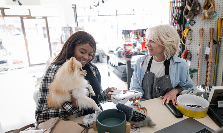 Woman holding a dog while talking to small business owner in a pet shop
