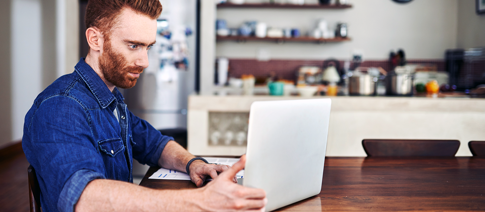 man looking at a laptop in a kitchen