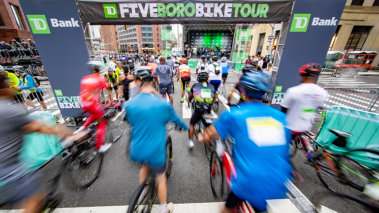 Bikes racing through the Five Boro Bike Tour starting line