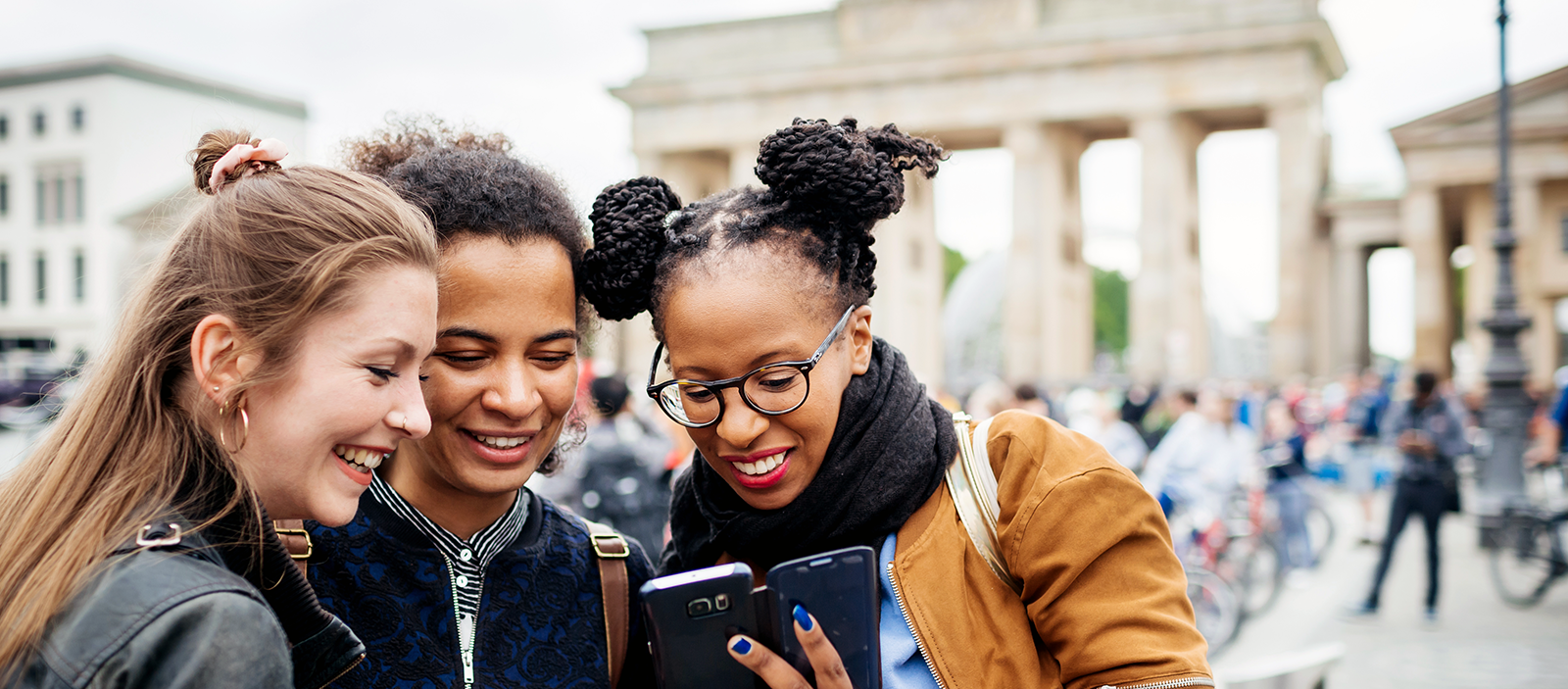 Group of women smiling in front of a European city background looking at a phone