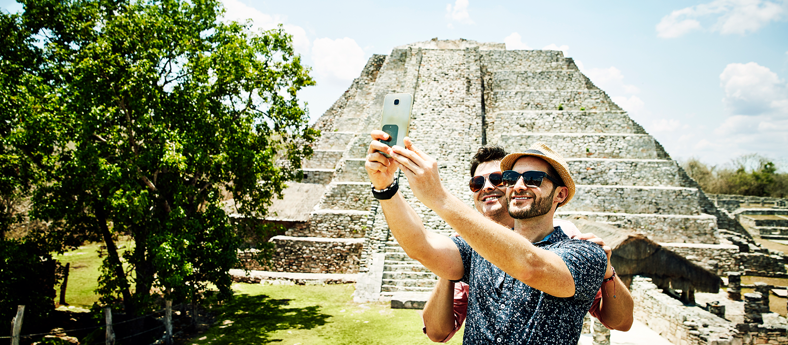 Two men taking a selfie together in front of pyramid in Mexico