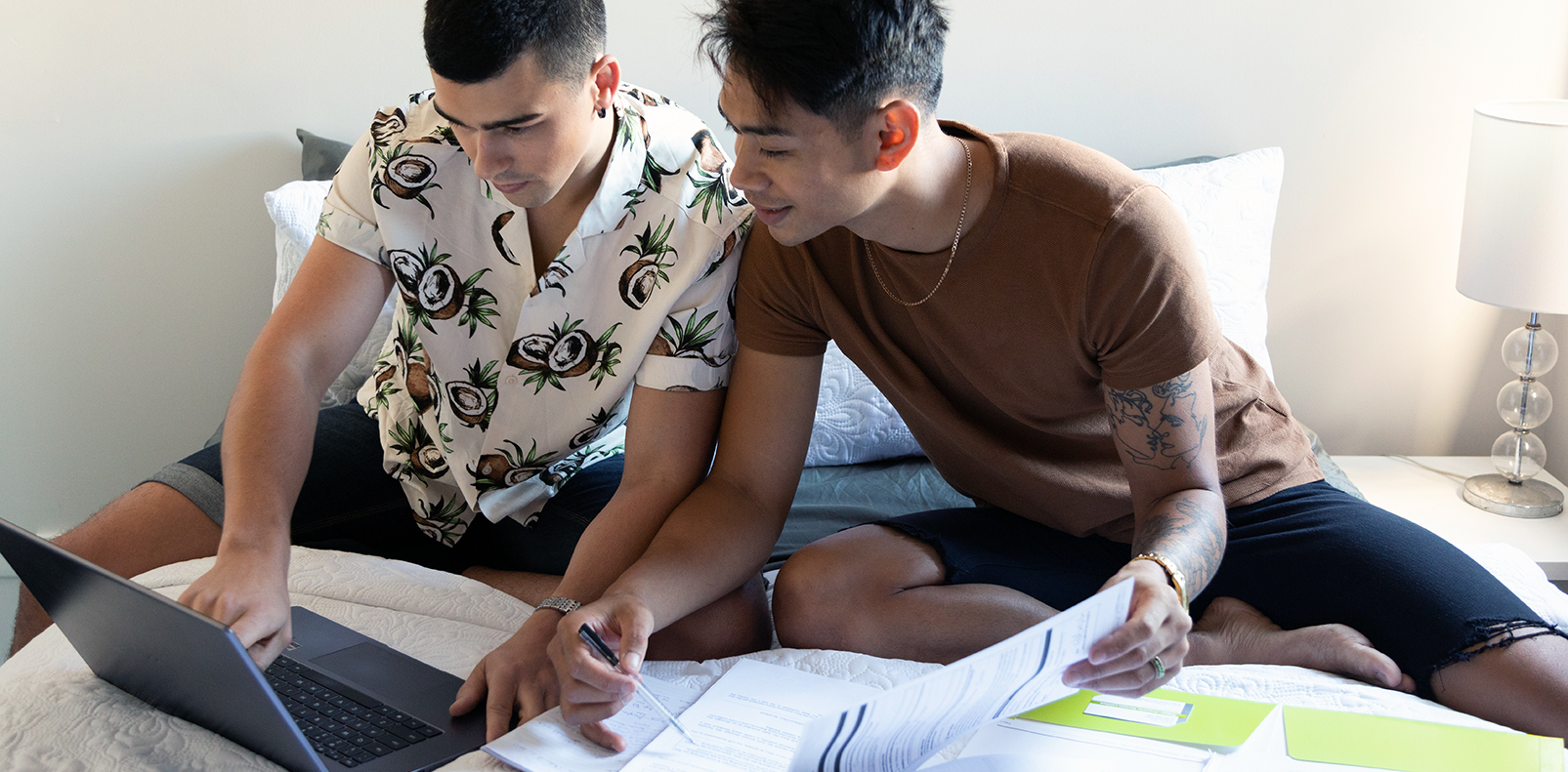 Two men sitting together and looking at paperwork and a laptop