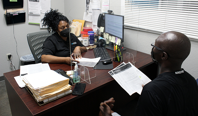 two people at a desk talking and looking at papers