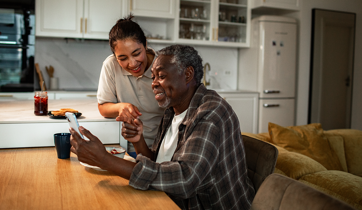Woman home care nurse helping older man with phone