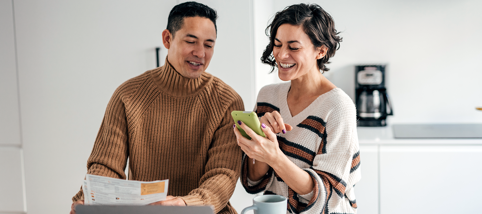Man holding documents while woman shows him something on her phone