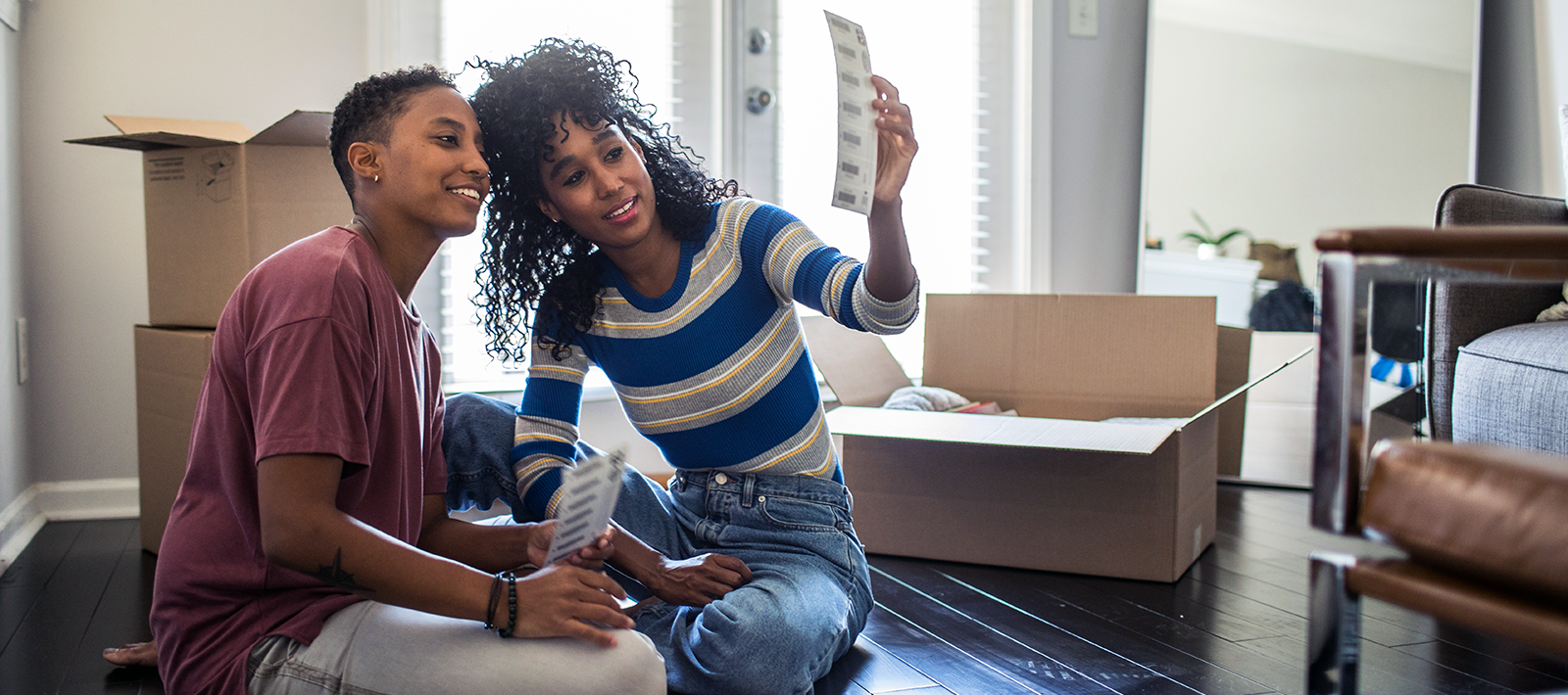 two women with moving boxes sitting on the floor unpacking