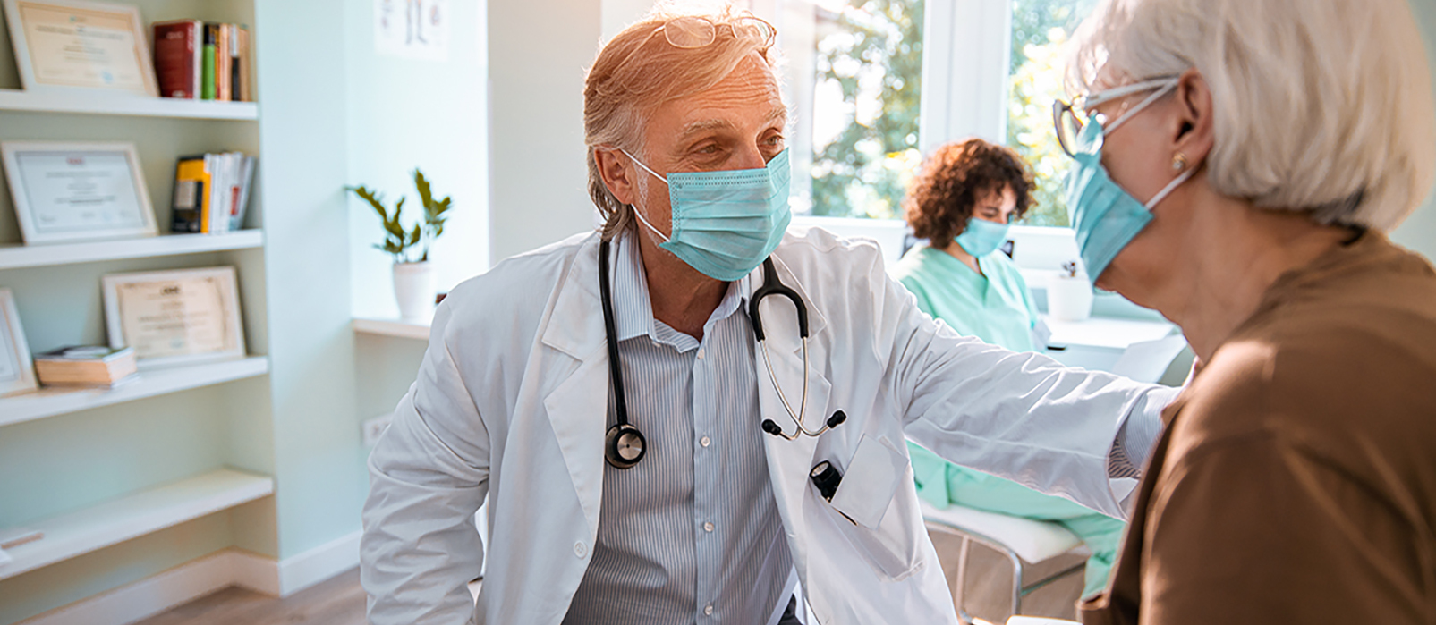 Older male doctor in mask talking to an elderly woman in a mask