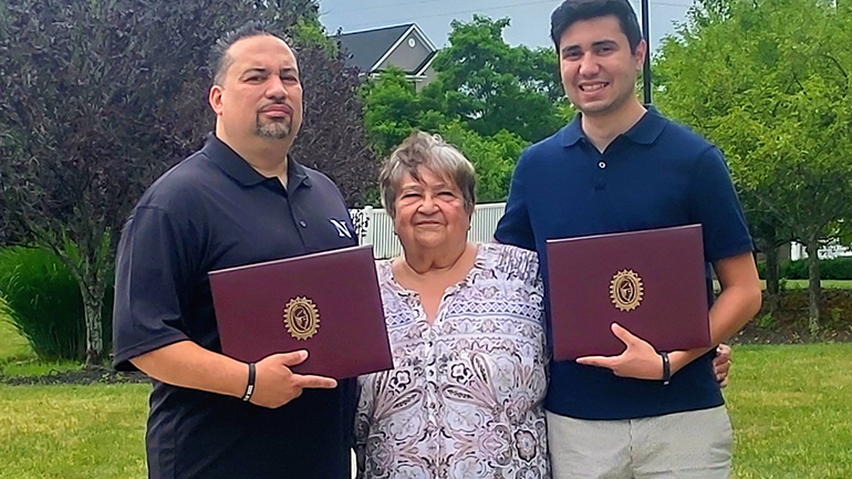 Juan with his mother and son holding their diplomas