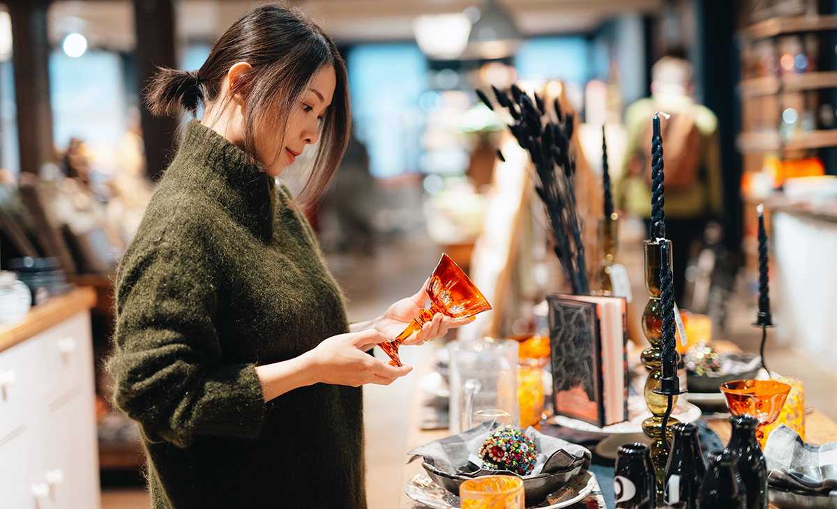 woman shopping in a store holding an orange wine glass