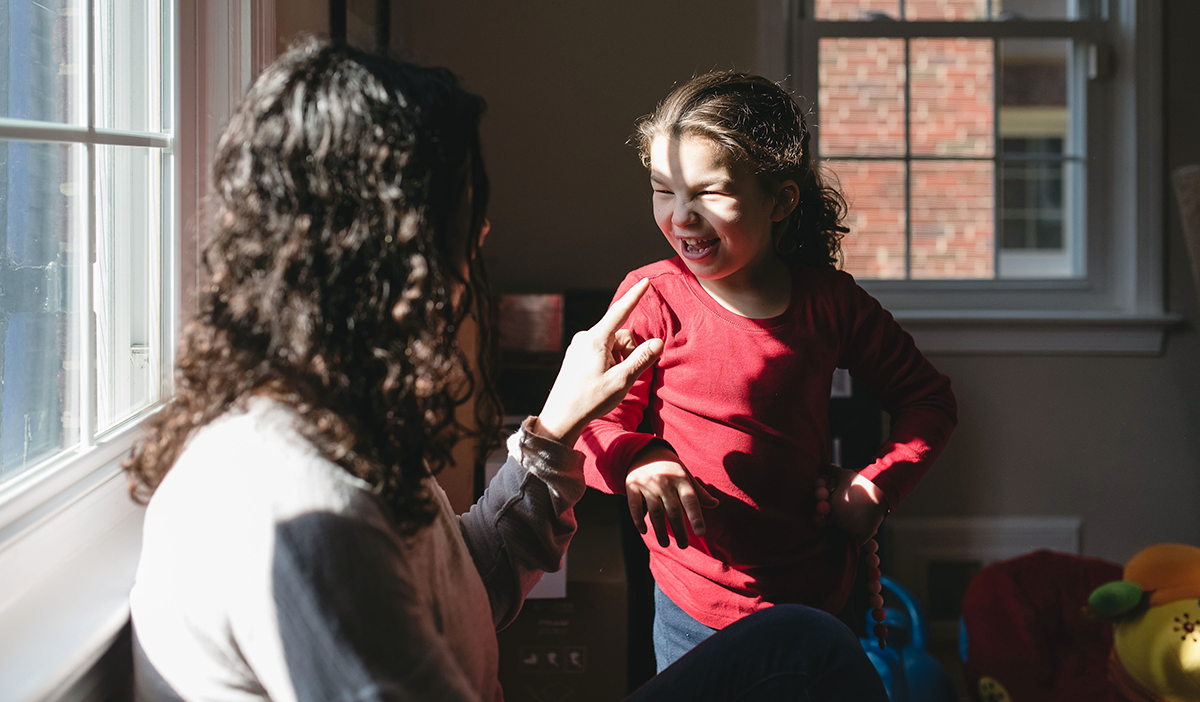 Young girl laughing while talking to a woman