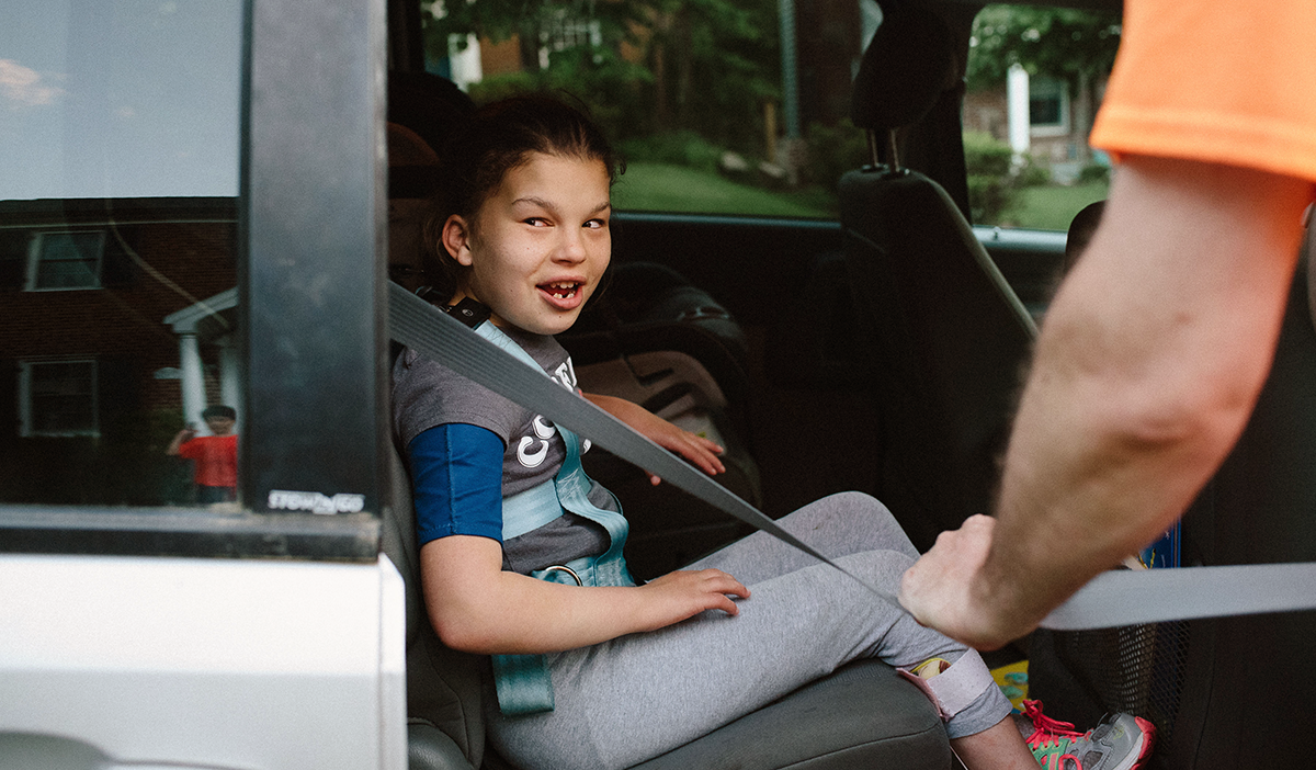 Young girl being helped into a car