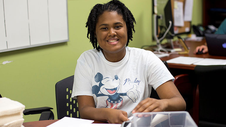 Simone smiling sitting at a desk
