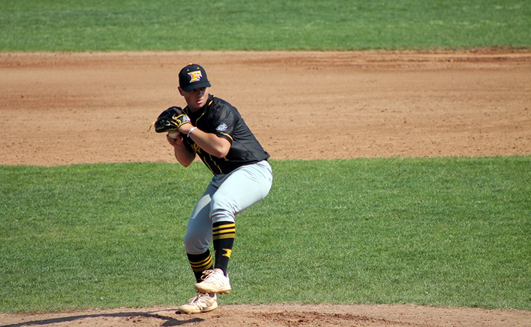 Young man in a black uniform throwing a baseball