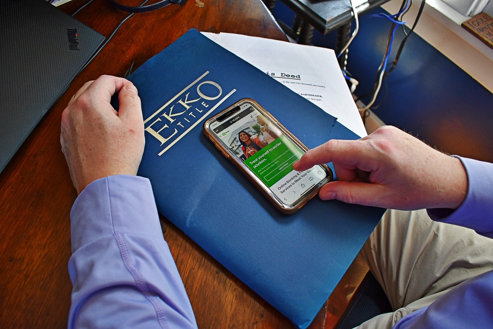 man on phone with documents looking at TD's website