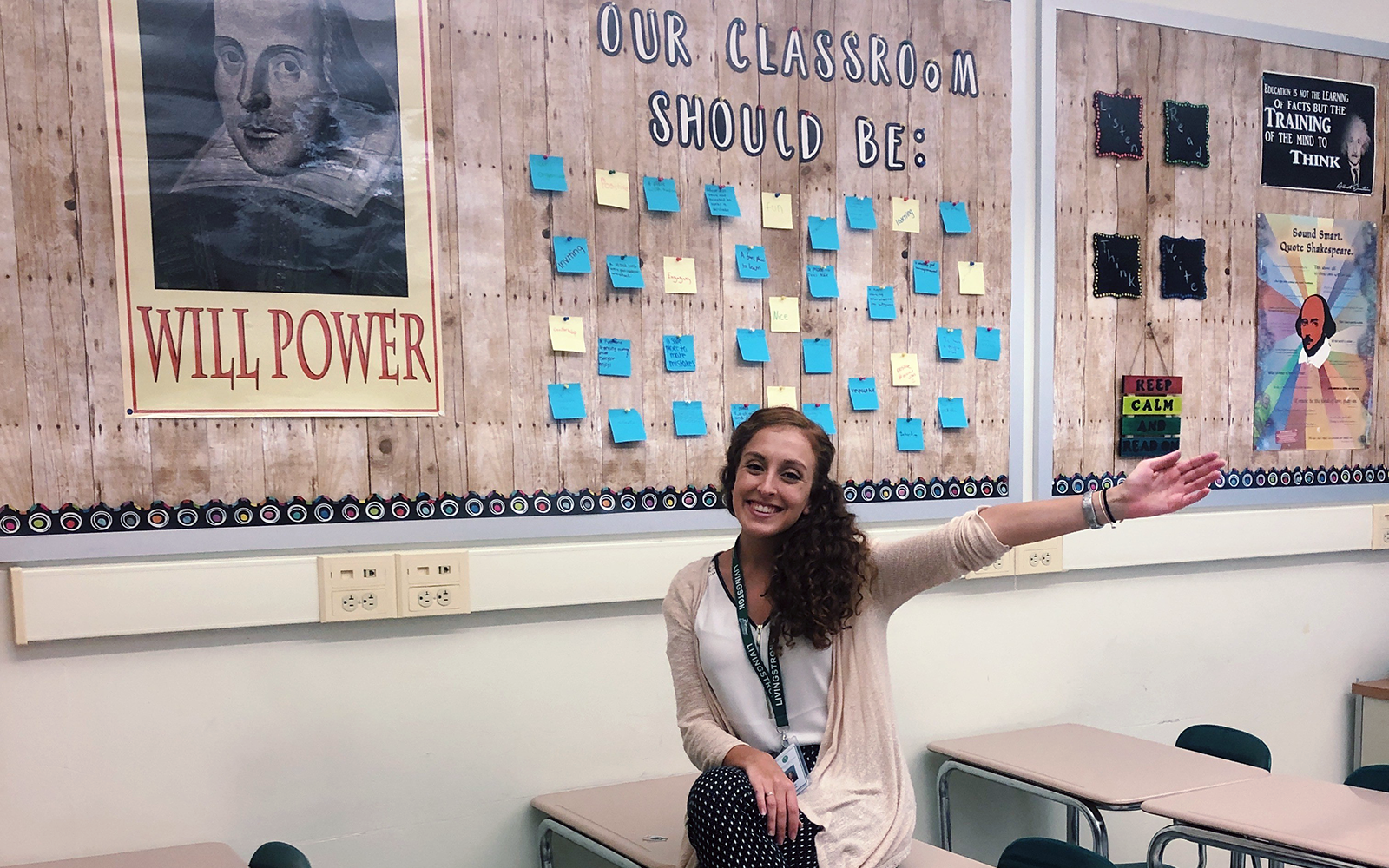 Woman smiling and holding her hand up in a classroom
