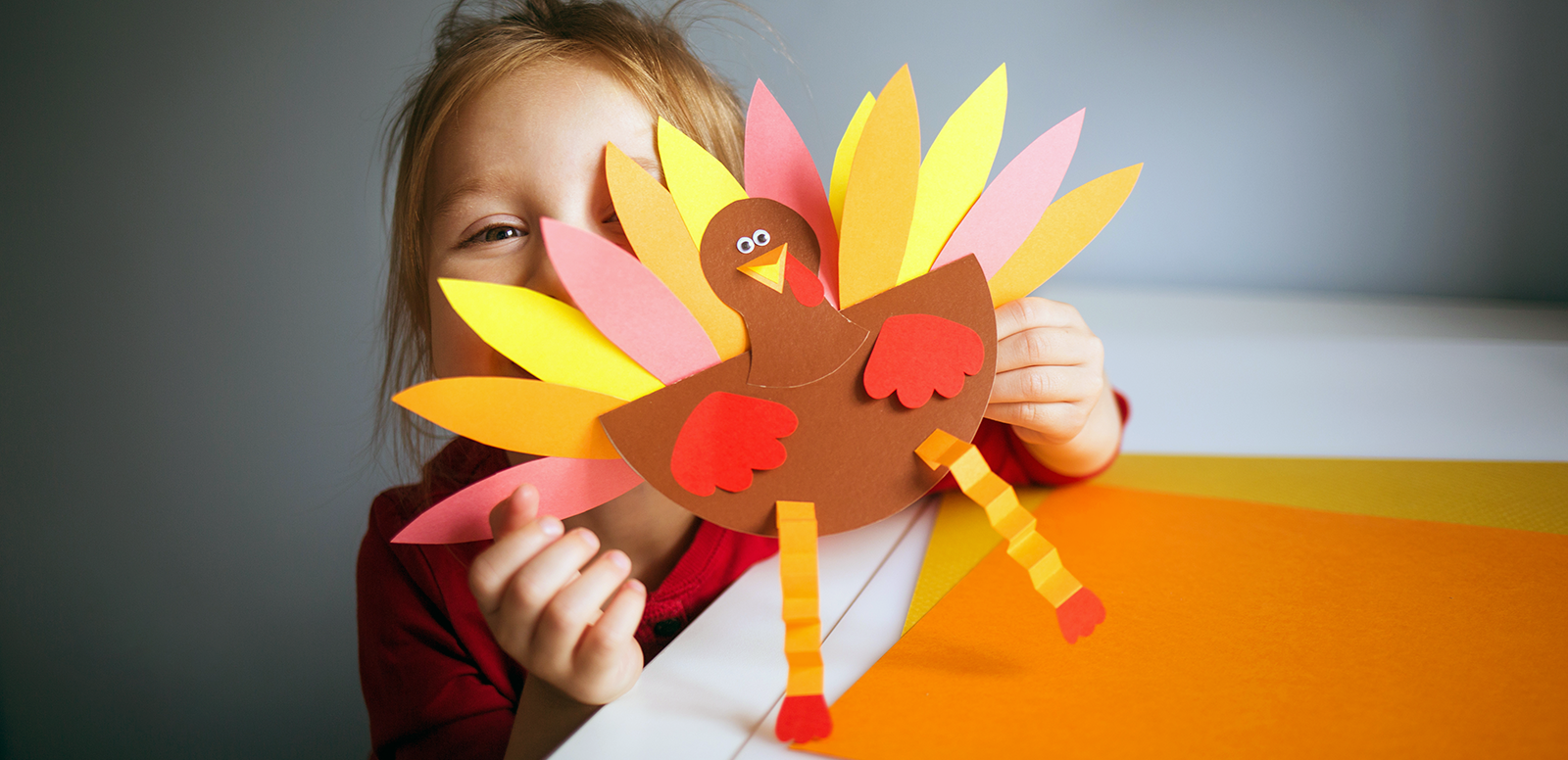 young girl holding a craft turkey